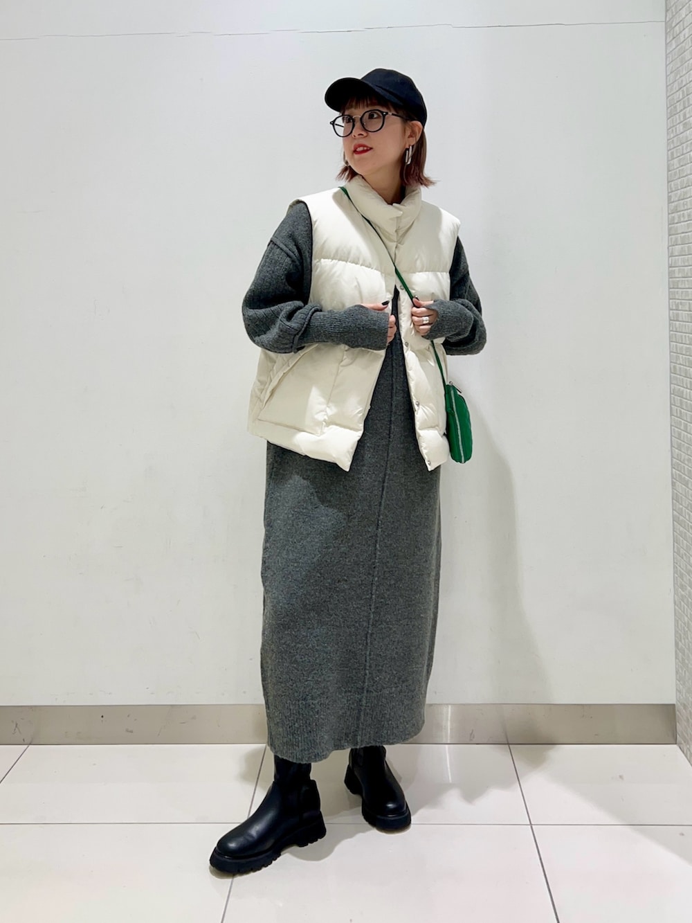 ブラック系のブーツ、グリーン系のショルダーバッグ、ホワイト系のダウンベストを着用したレディースの秋コーディネートの8枚目の写真