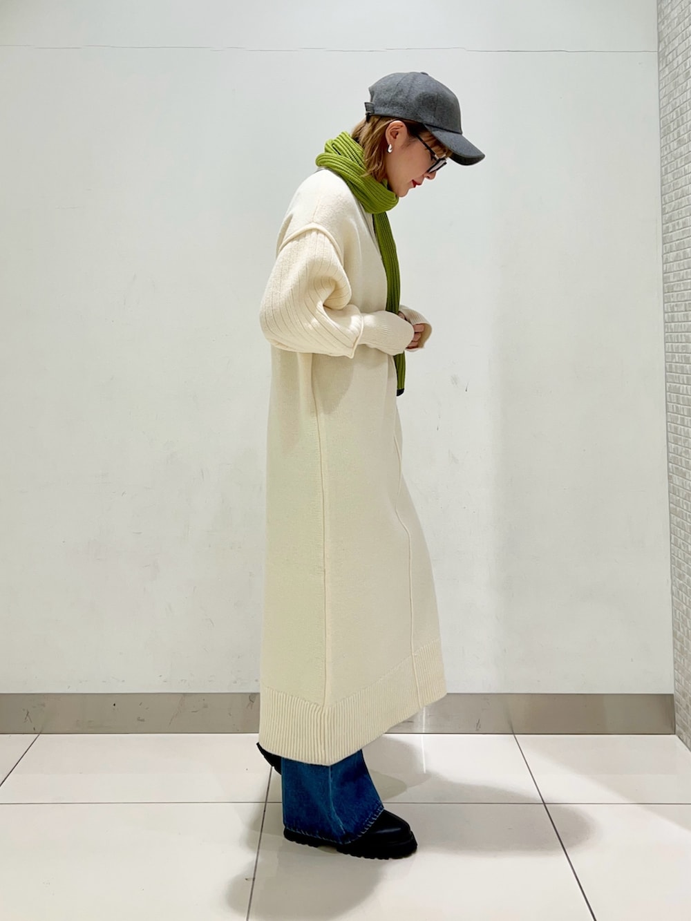 シルバー系のショルダーバッグ、ホワイト系のワンピース、ブルー系のデニムパンツを着用したレディースの冬コーディネートの5枚目の写真