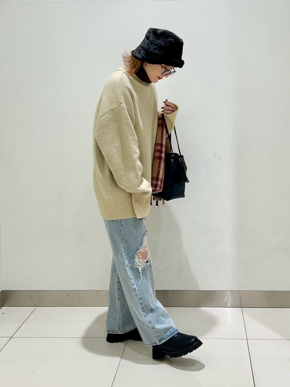 ブラック系のショルダーバッグ、ブルー系のデニムパンツ、ブラック系のブーツを着用したレディースの冬コーディネートの5枚目の写真