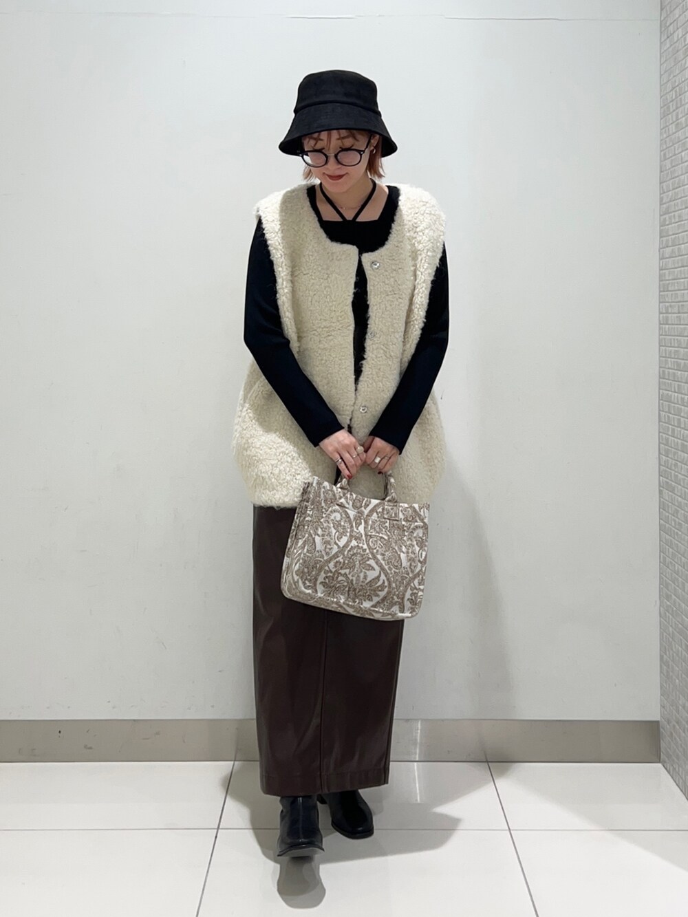 ベージュ系のトートバッグ、ブラック系のニット/セーター、ブラウン系のスカートを着用したレディースの秋コーディネートの6枚目の写真