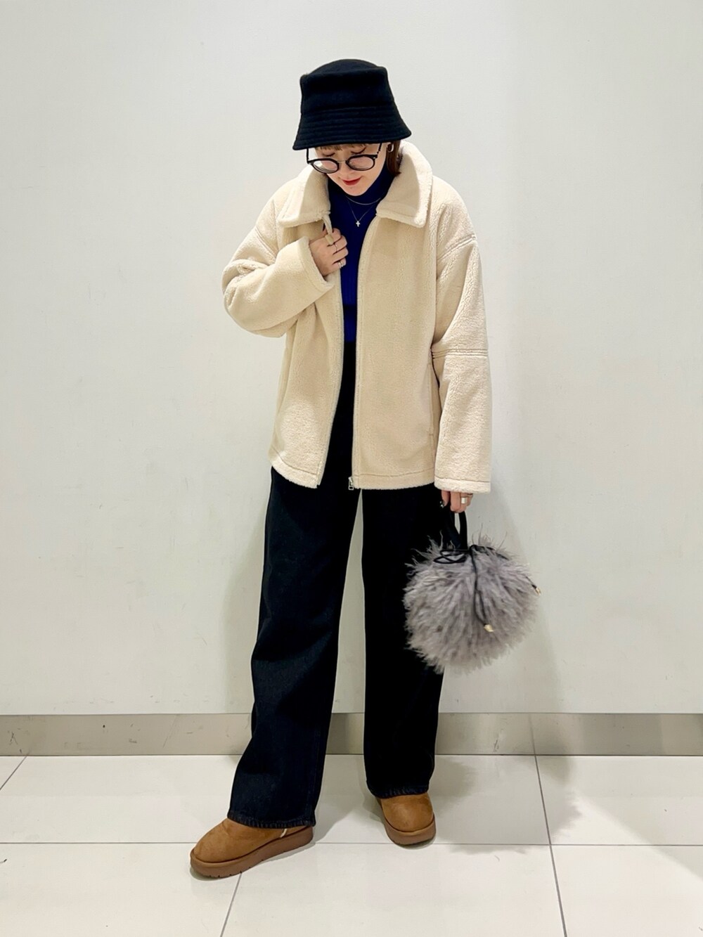 ブラック系のデニムパンツ、ブルー系のニット/セーター、ホワイト系のブルゾンを着用したレディースの冬コーディネートの6枚目の写真