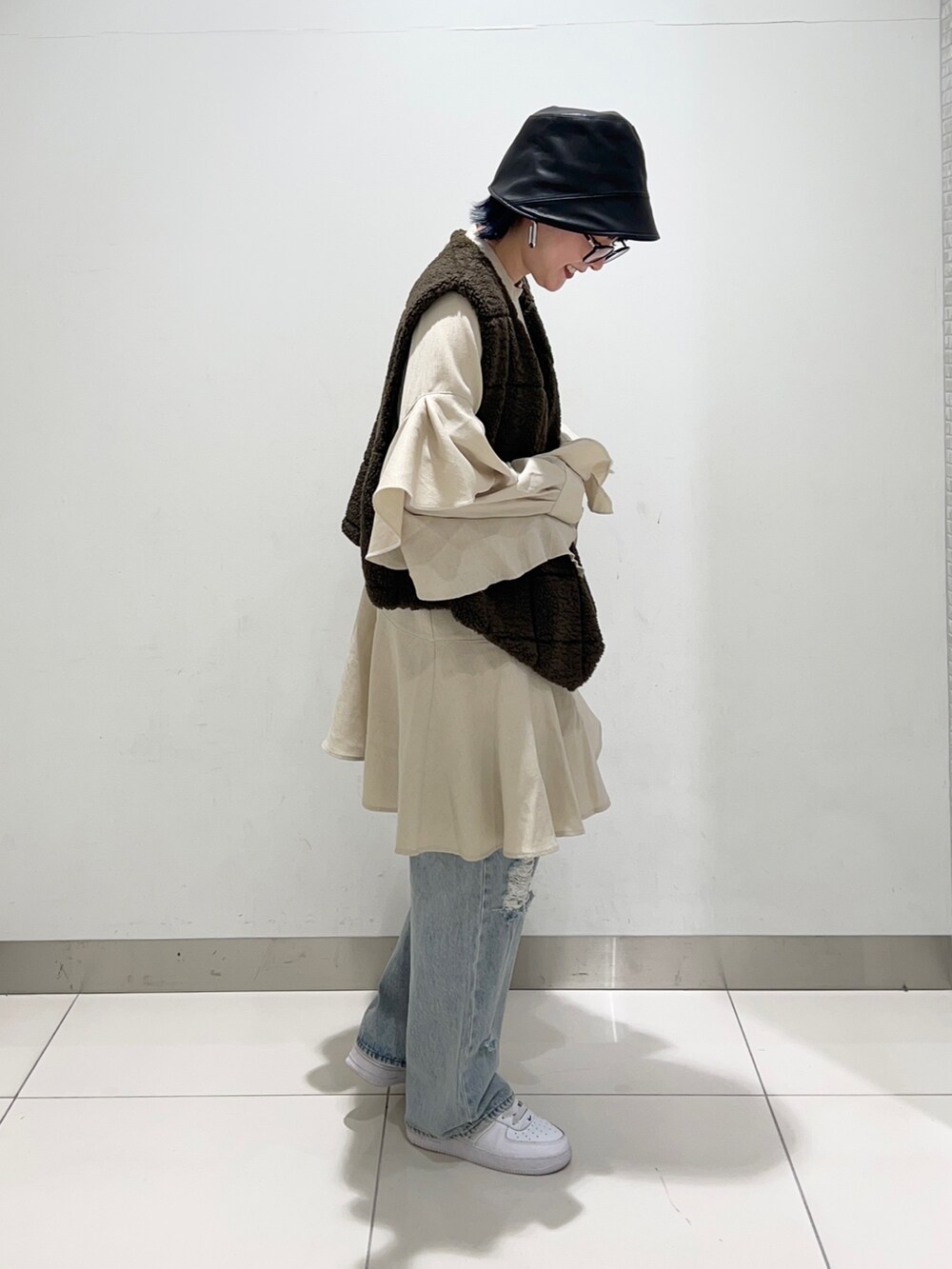 ブラウン系のベスト、ベージュ系のワンピース/ドレス、ブルー系のデニムパンツを着用したレディースの秋コーディネートの5枚目の写真