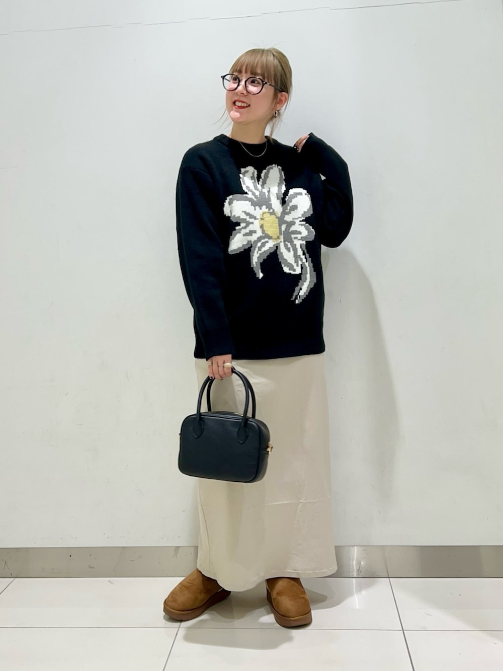 ブラック系のボストンバッグ、ベージュ系のスカート、ブラック系のニット/セーターを着用したレディースの冬コーディネートの7枚目の写真