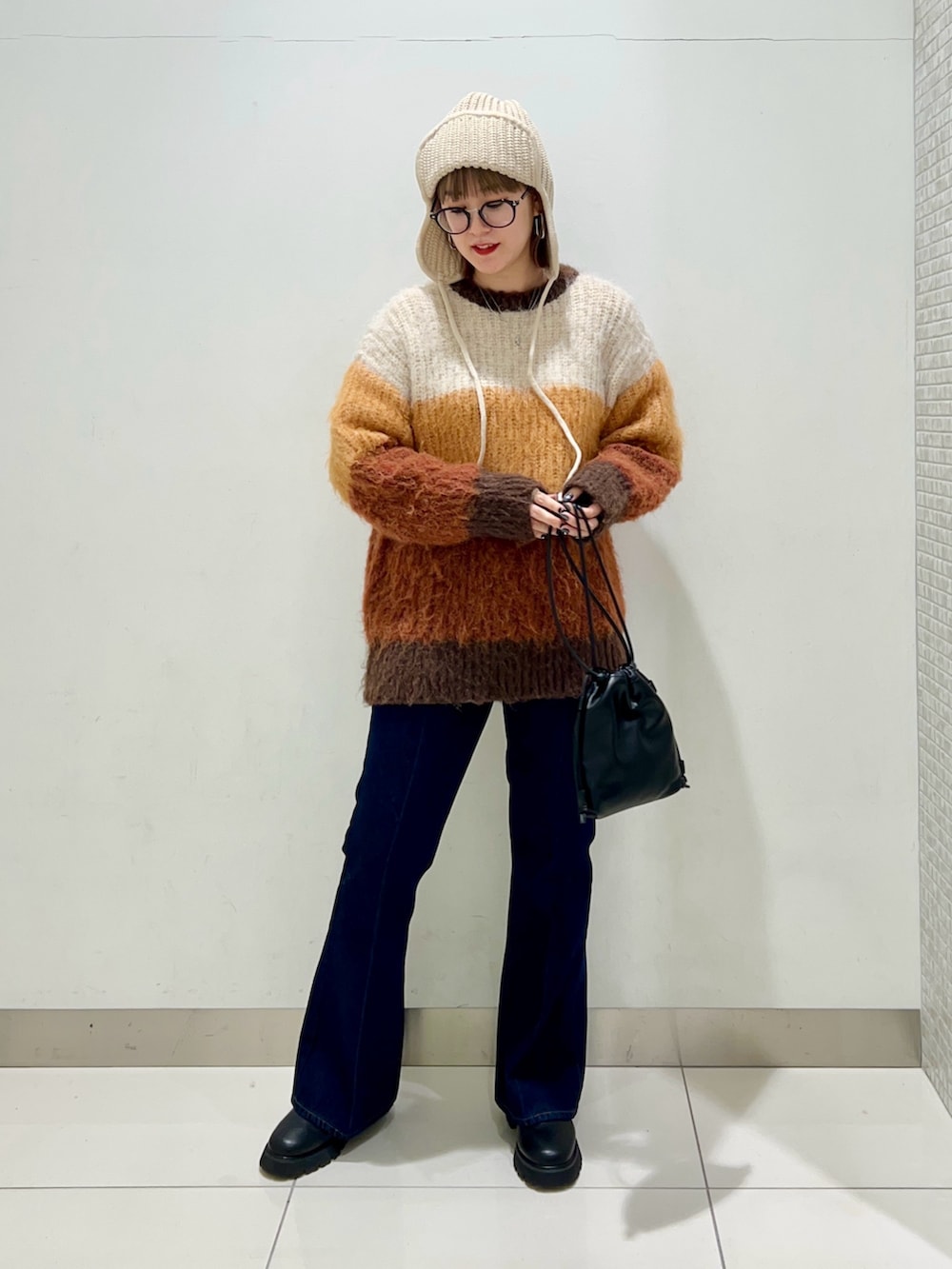 ブルー系のデニムパンツ、ブラック系のショルダーバッグ、ブラック系のブーツを着用したレディースの冬コーディネートの6枚目の写真