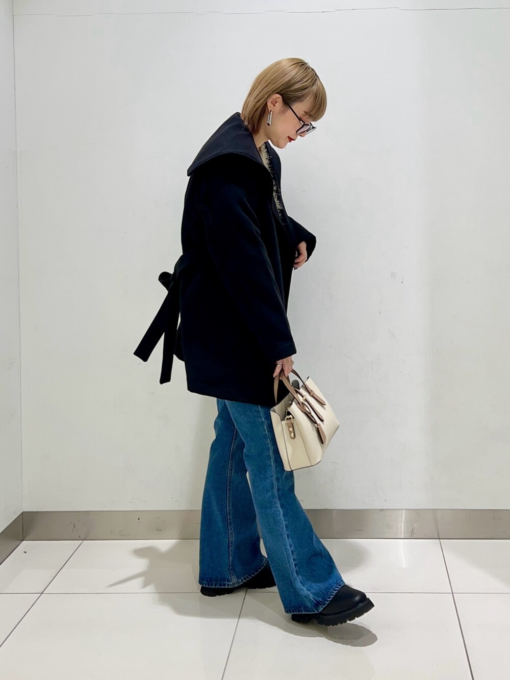 ブラック系のブーツ、ホワイト系のハンドバッグ、ブラック系のその他アウターを着用したレディースの冬コーディネートの5枚目の写真