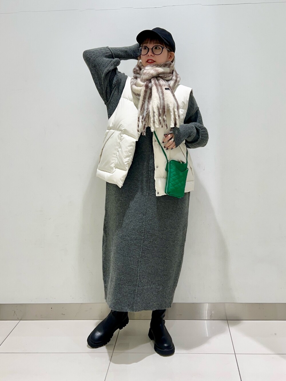 ブラック系のブーツ、グリーン系のショルダーバッグ、ホワイト系のダウンベストを着用したレディースの秋コーディネートの6枚目の写真