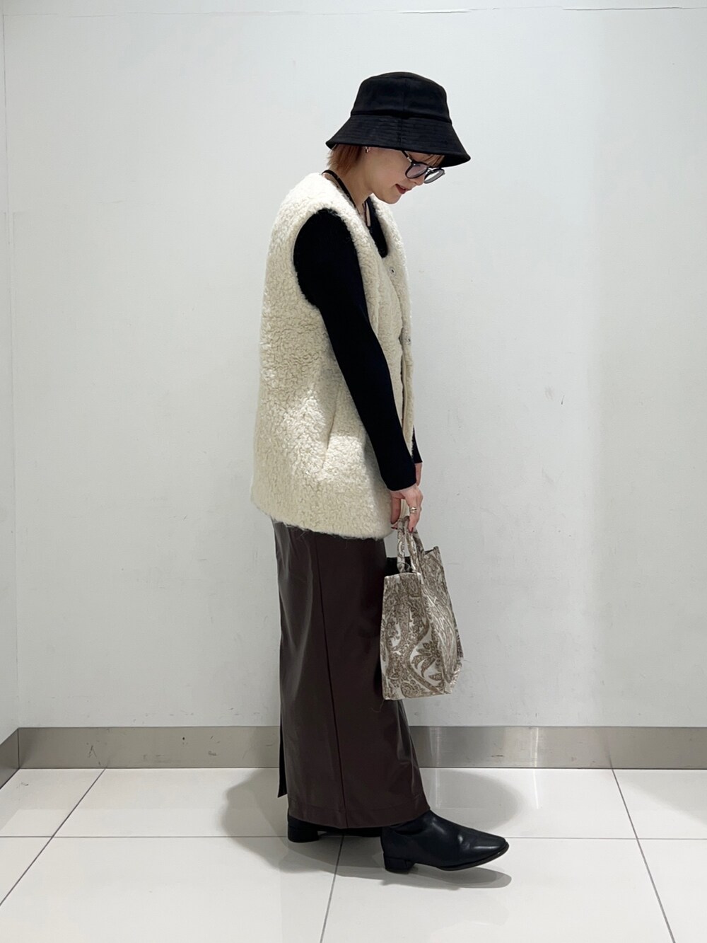 ベージュ系のトートバッグ、ブラック系のニット/セーター、ブラウン系のスカートを着用したレディースの秋コーディネートの5枚目の写真