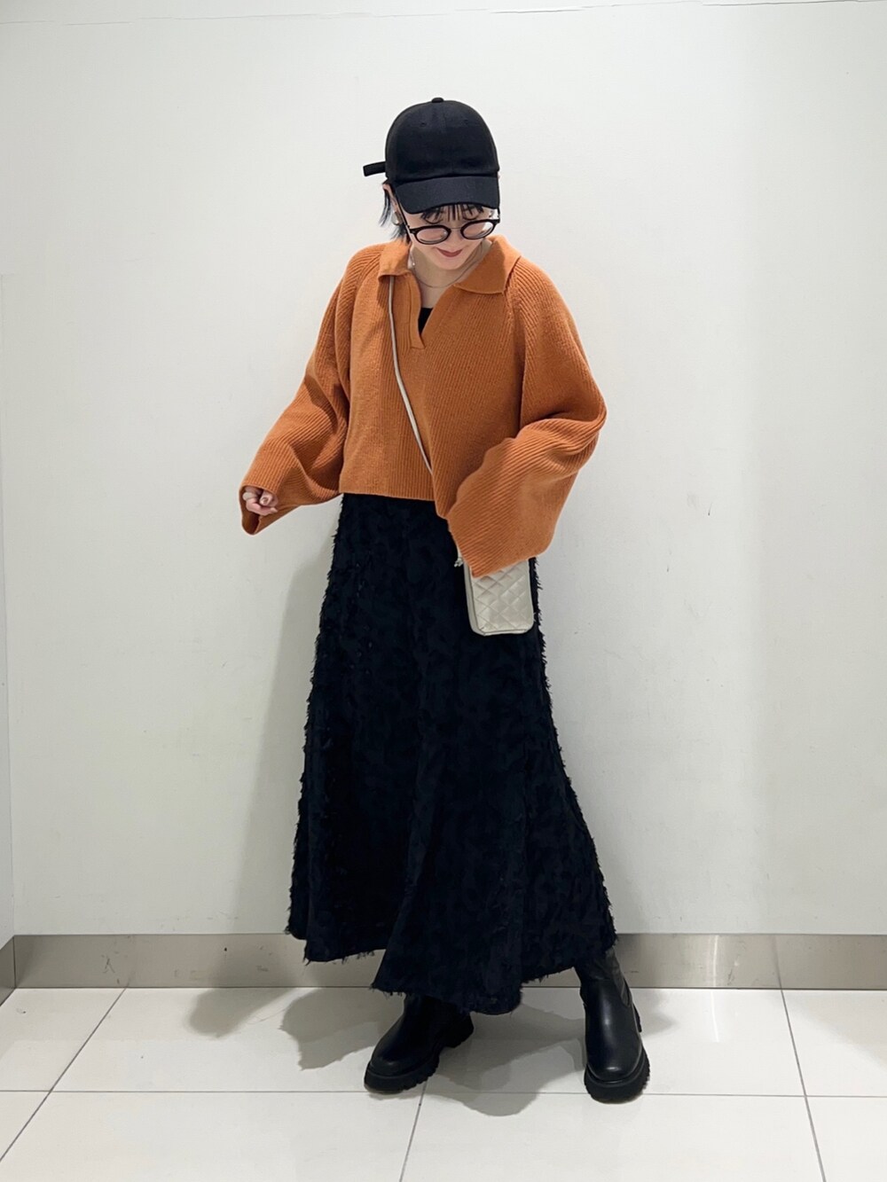 ブラック系のワンピース、オレンジ系のニット/セーター、ブラック系のブーツを着用したレディースの秋コーディネートの6枚目の写真