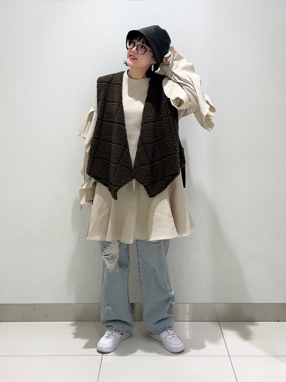 ブラウン系のベスト、ベージュ系のワンピース/ドレス、ブルー系のデニムパンツを着用したレディースの秋コーディネートの2枚目の写真