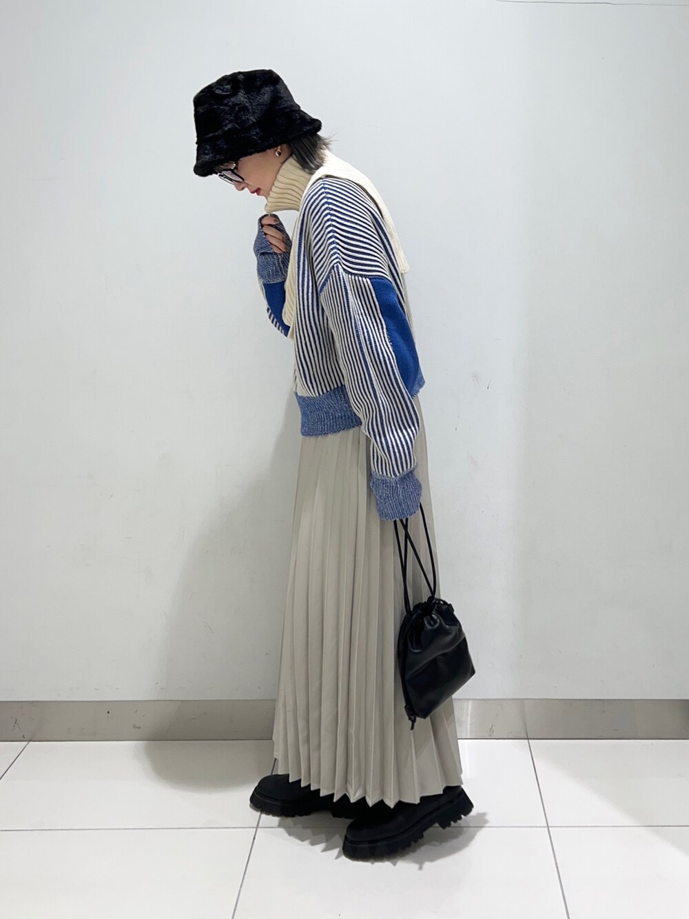 ベージュ系のスカート、ブラック系のショルダーバッグ、ブラック系のブーツを着用したレディースの秋コーディネートの3枚目の写真