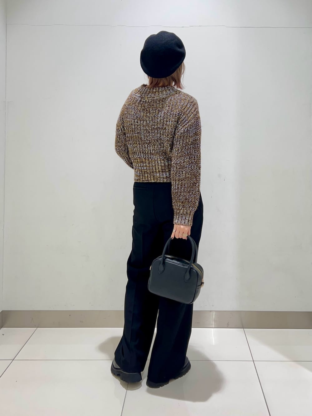 ブラック系のボストンバッグ、ブラック系のスラックス、ブラック系のブーツを着用したレディースの秋コーディネートの7枚目の写真