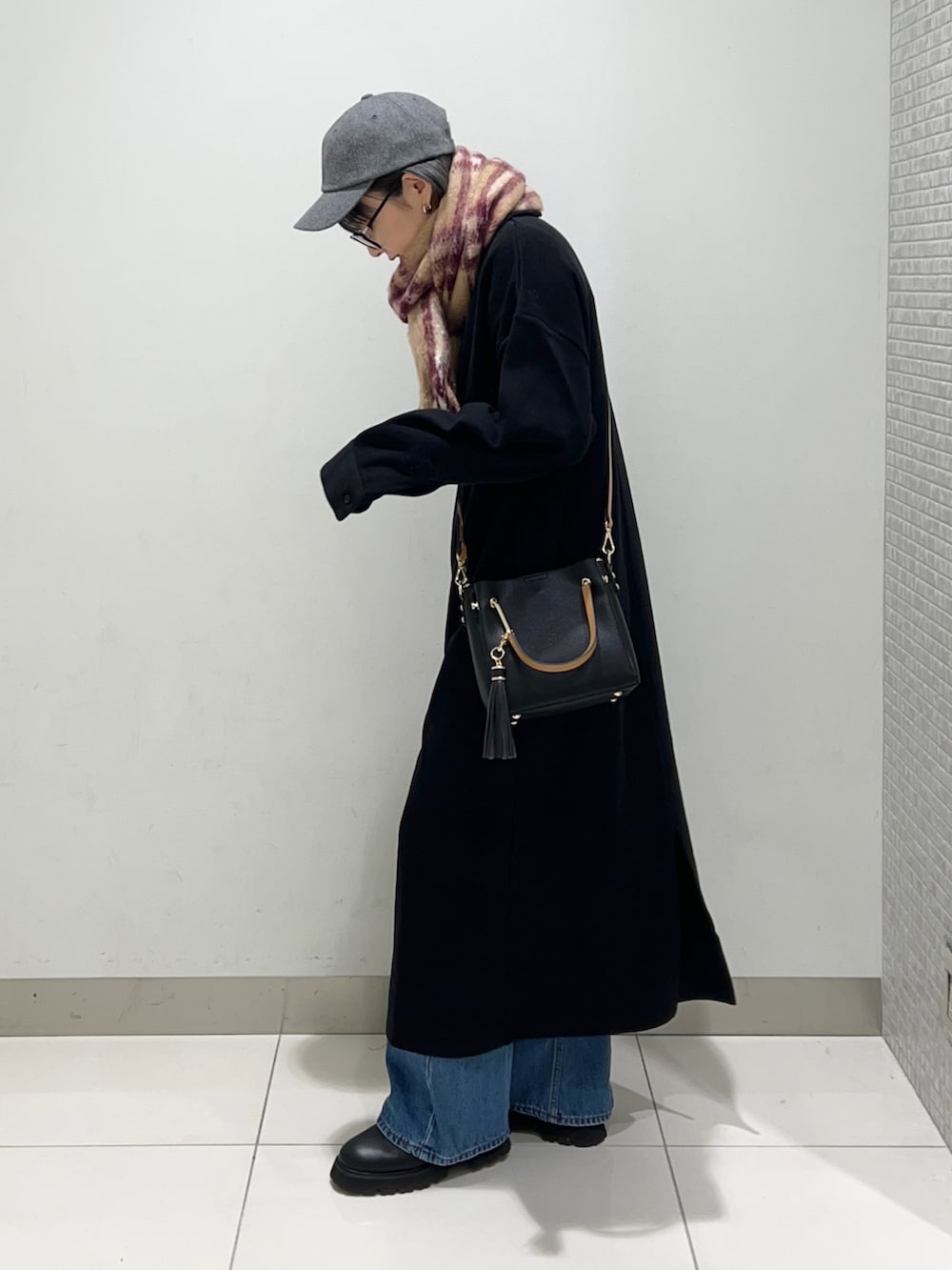 ブラック系のトートバッグ、ブラック系のワンピース、ブラック系のブーツを着用したレディースの秋コーディネートの2枚目の写真