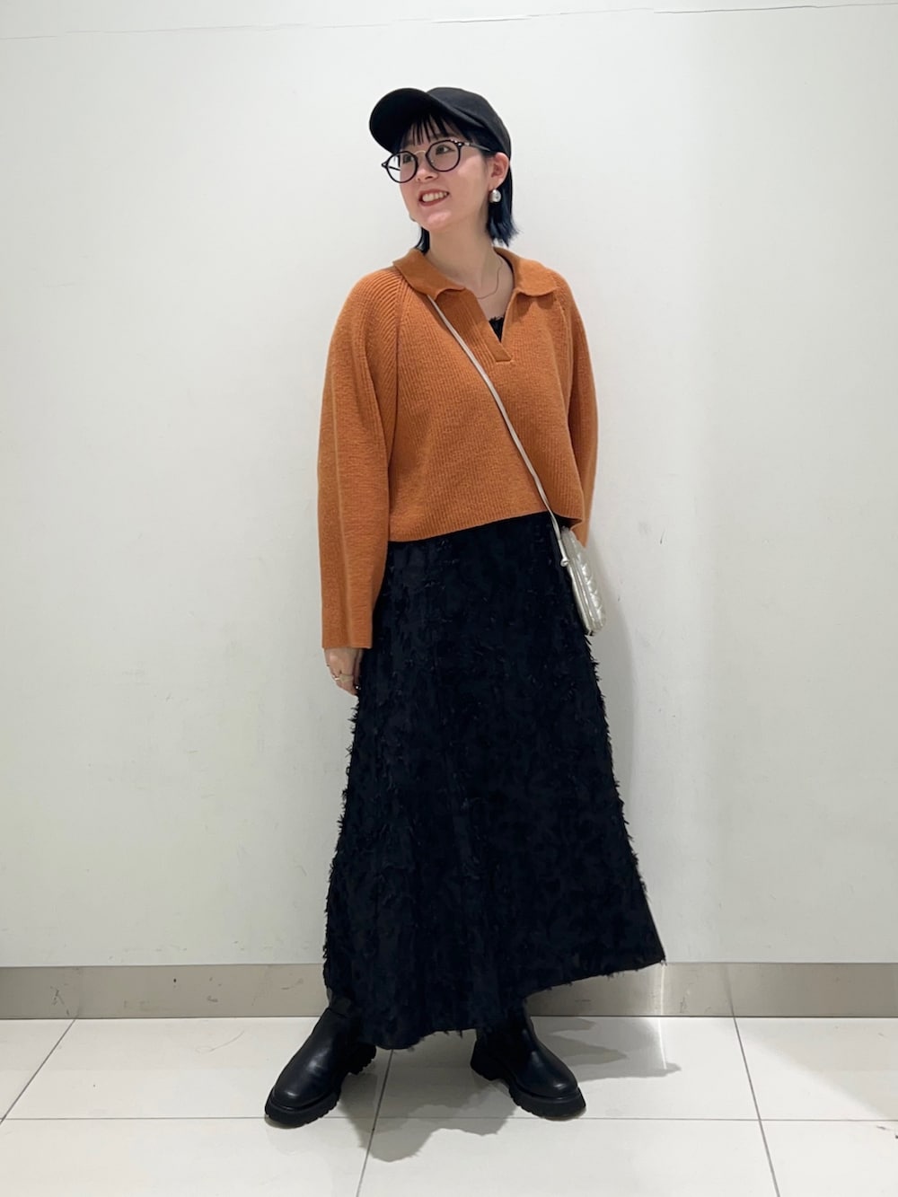 ブラック系のワンピース、オレンジ系のニット/セーター、ブラック系のブーツを着用したレディースの秋コーディネートの7枚目の写真