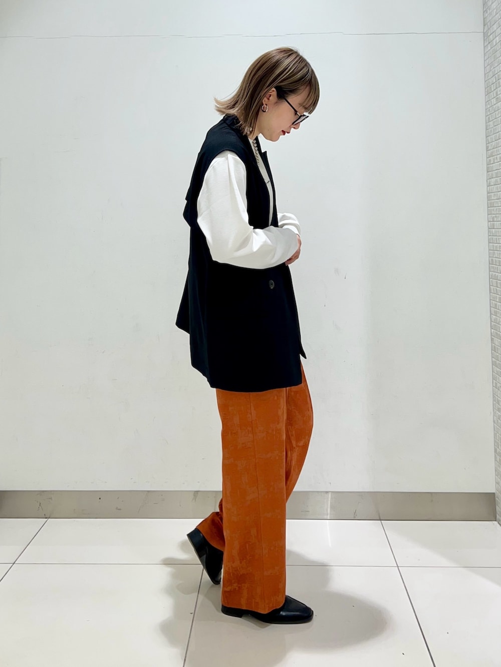 ブラウン系のショルダーバッグ、ブラック系のその他アウター、オレンジ系のその他パンツを着用したレディースの春コーディネートの5枚目の写真