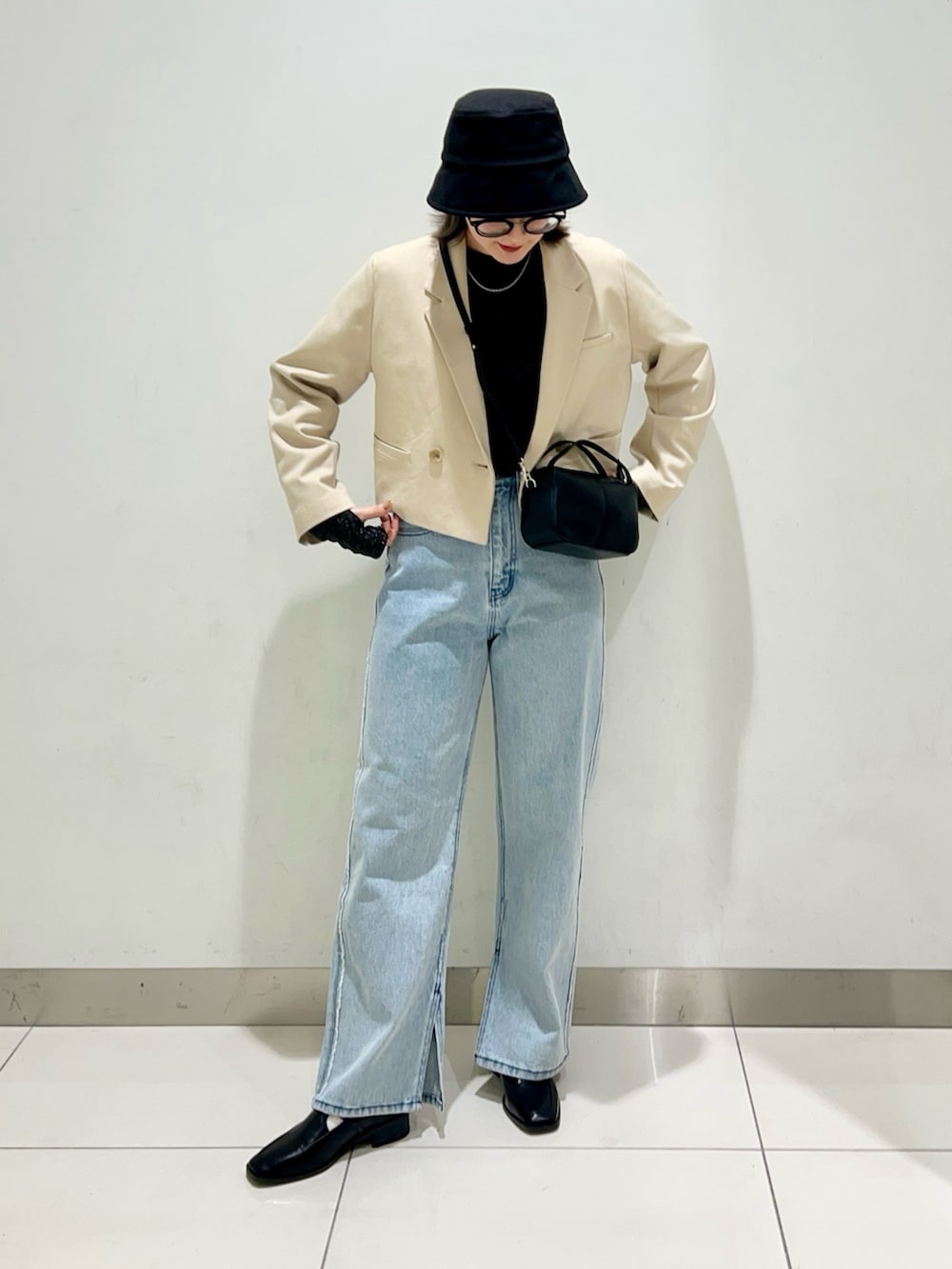 ブラック系のTシャツ/カットソー、ベージュ系のその他アウター、ブラック系のショルダーバッグを着用したレディースの春コーディネートの2枚目の写真