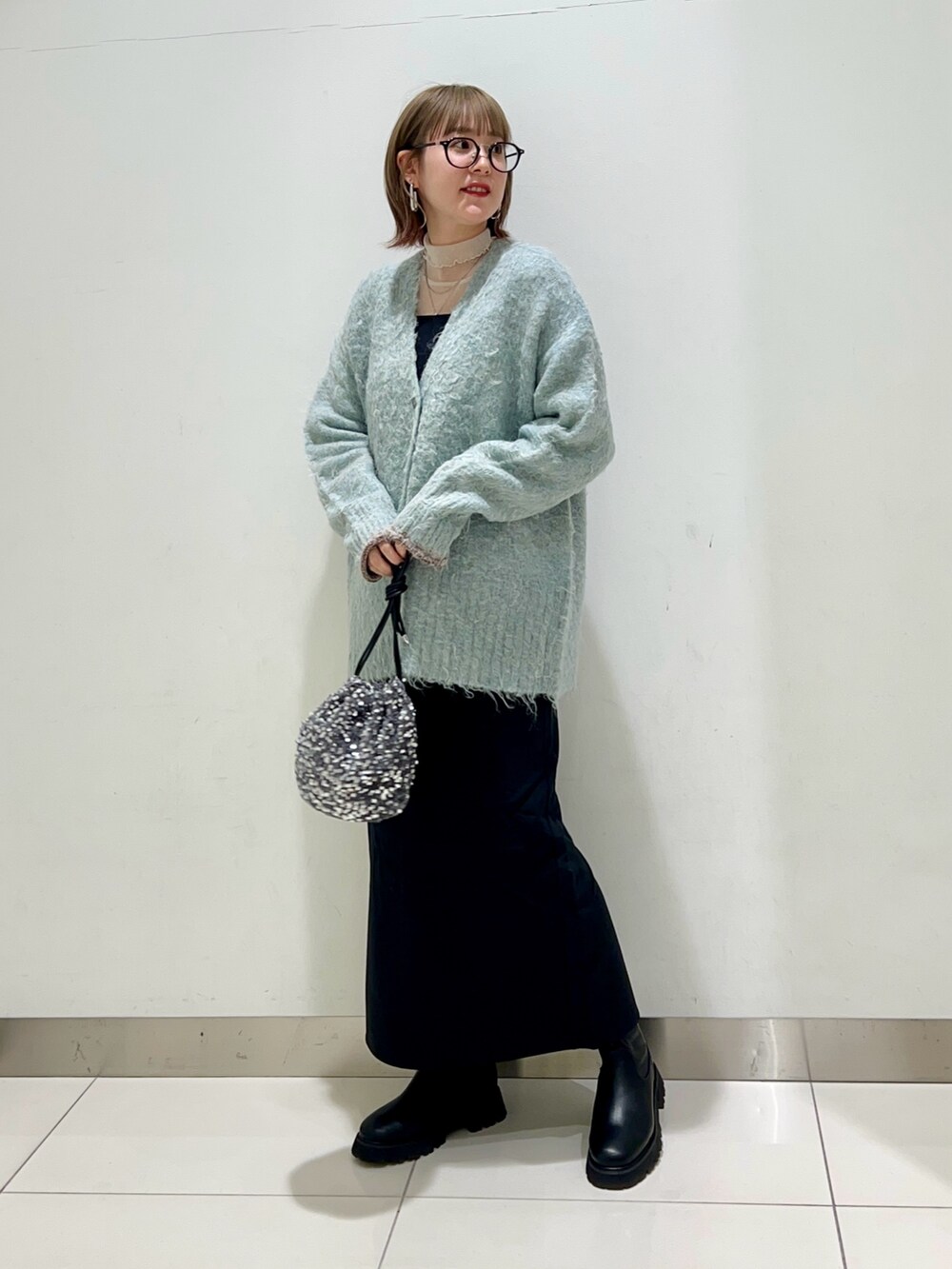ブルー系のカーディガン/ボレロ、ブラック系のワンピース、ブラック系のブーツを着用したレディースの秋コーディネートの6枚目の写真
