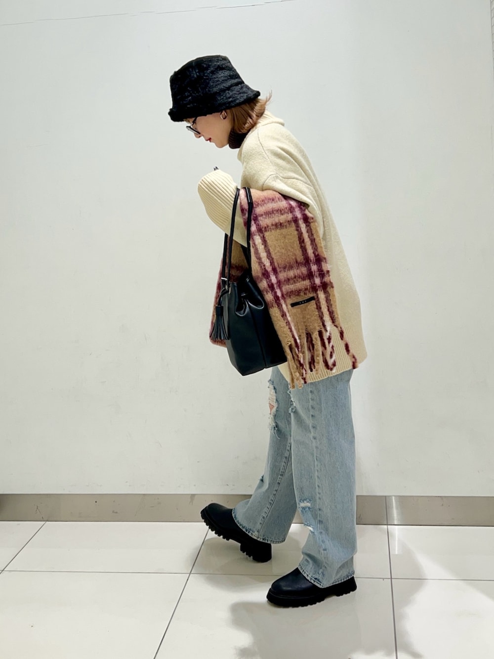 ブラック系のショルダーバッグ、ブルー系のデニムパンツ、ブラック系のブーツを着用したレディースの冬コーディネートの3枚目の写真