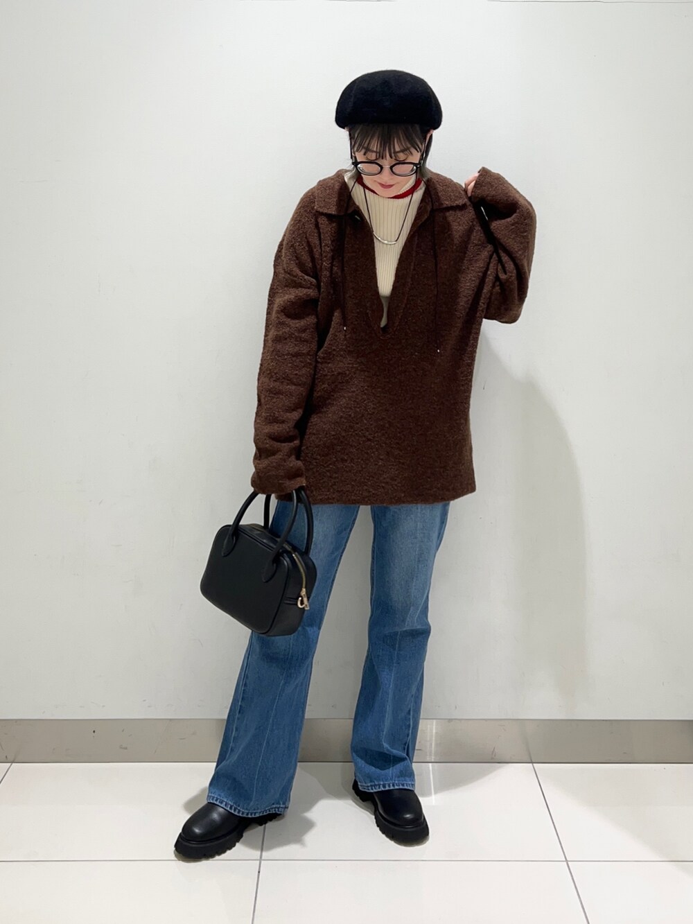 ブラック系のブーツ、ブルー系のデニムパンツ、ブラック系のボストンバッグを着用したレディースの秋コーディネートの2枚目の写真