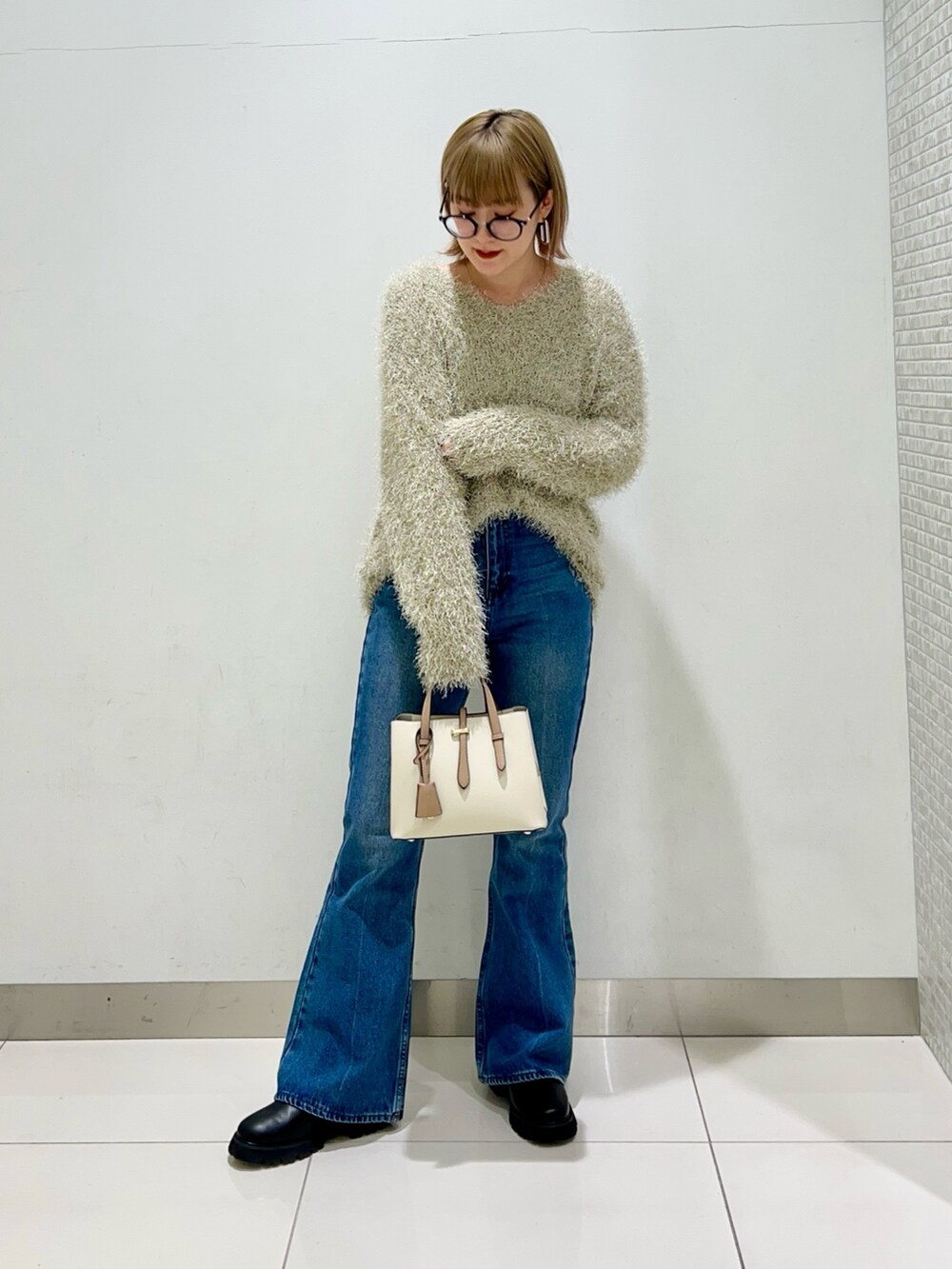 ブラック系のブーツ、ホワイト系のハンドバッグ、ブラック系のその他アウターを着用したレディースの冬コーディネートの7枚目の写真