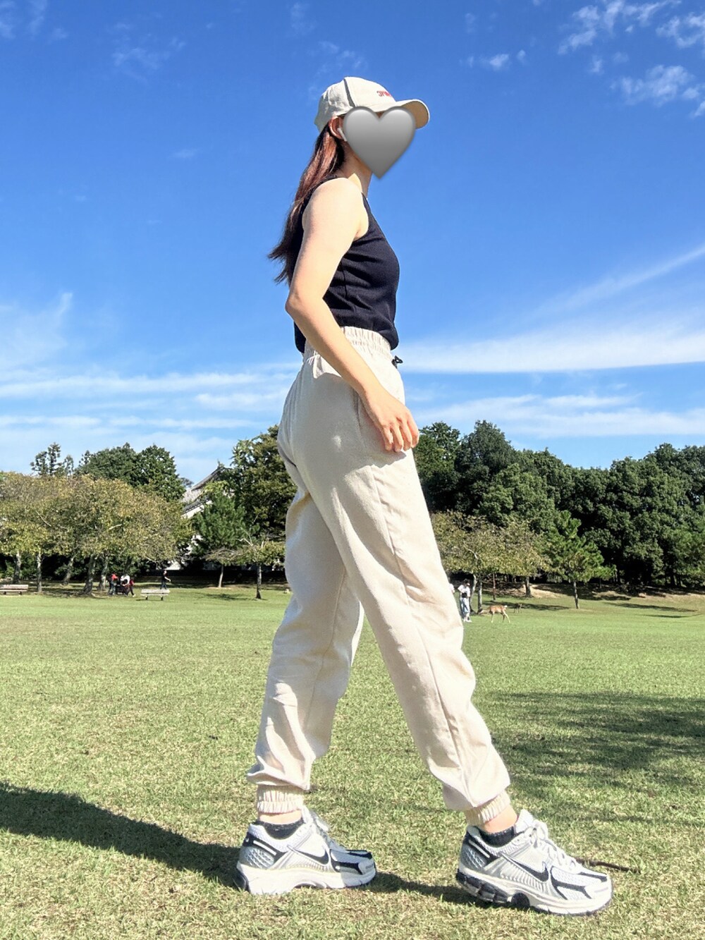 ベージュ系のスウェットパンツ、ブラック系のキャミソール、ホワイト系のスニーカーを着用したレディースの秋コーディネートの2枚目の写真