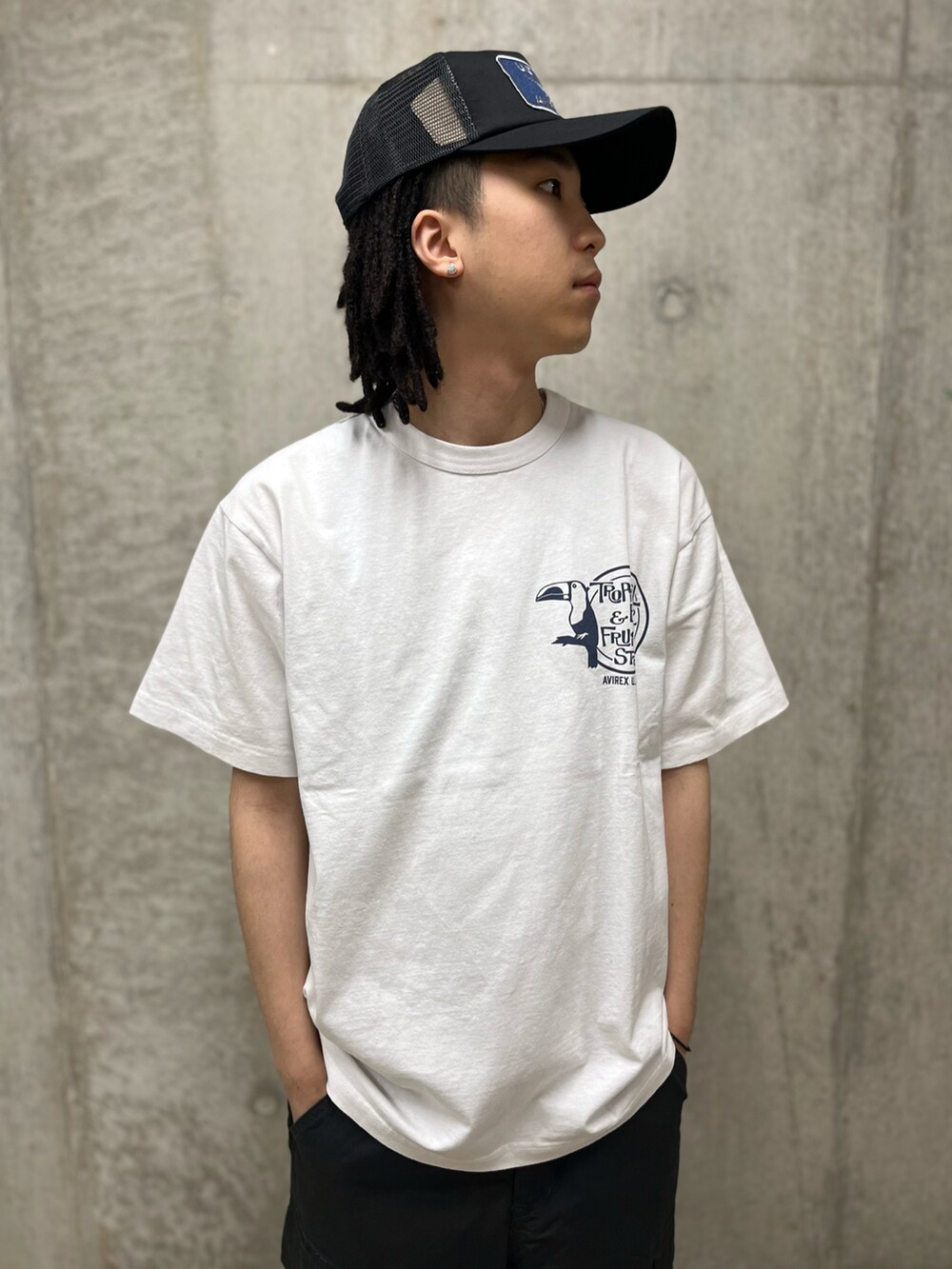 グレー系のカーゴパンツ、ホワイト系のTシャツ/カットソー、ブラック系のキャップを着用したメンズの春コーディネートの3枚目の写真