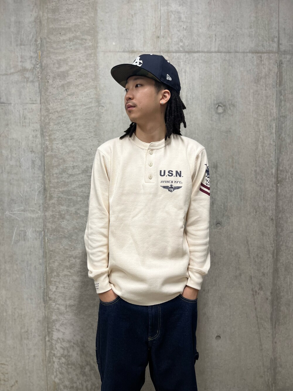 ベージュ系のTシャツ/カットソー、ブルー系のデニムパンツ、ブルー系のキャップを着用したメンズの秋コーディネートの3枚目の写真