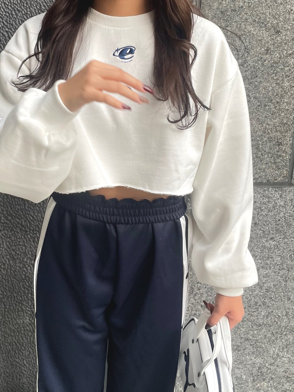 ホワイト系のスウェット、ブルー系のその他パンツ、ホワイト系のハンドバッグを着用したレディースの秋コーディネートの3枚目の写真