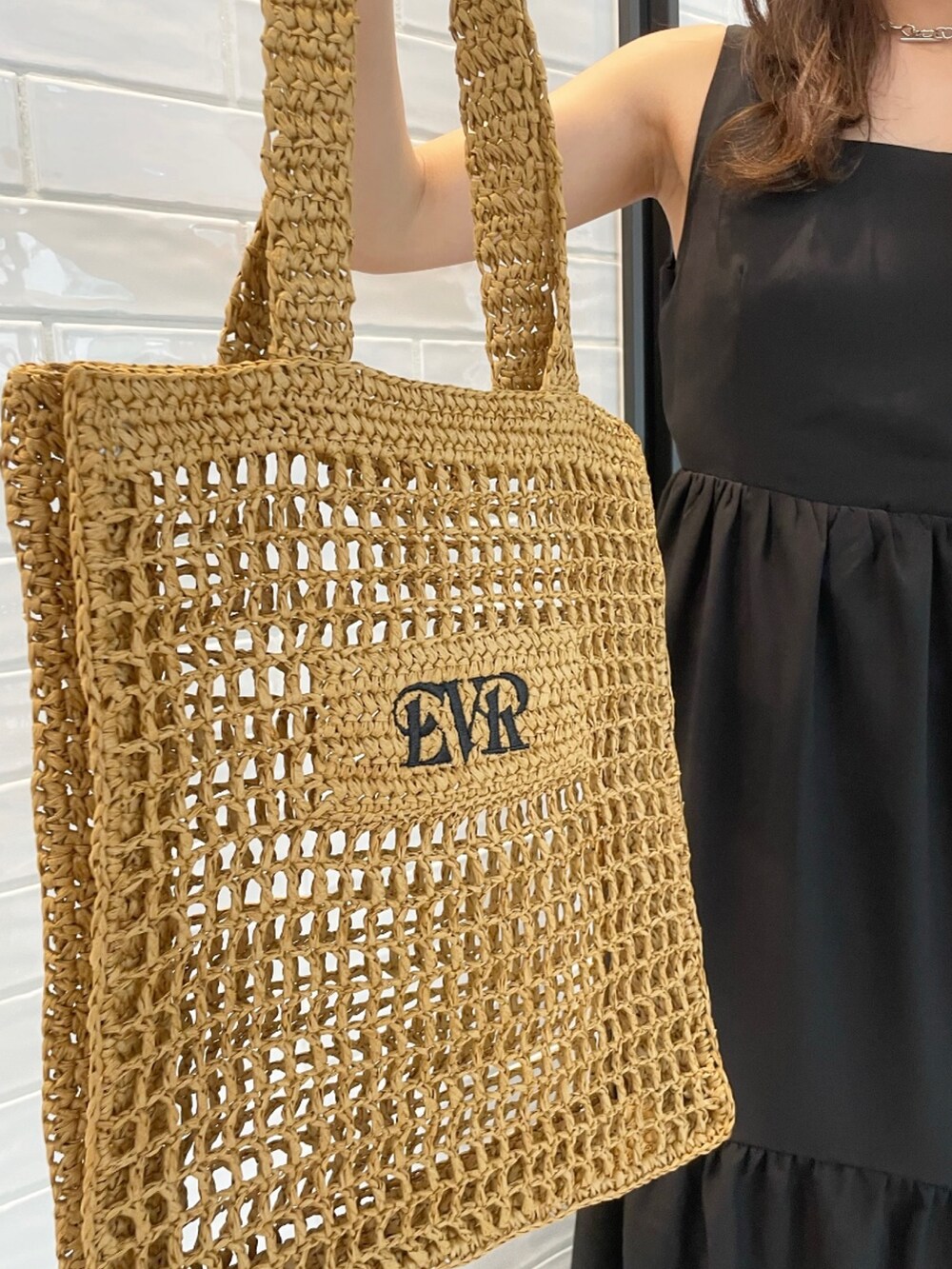 ブラック系のワンピース、ベージュ系のトートバッグ、ホワイト系のサンダルを着用したレディースの夏コーディネートの5枚目の写真