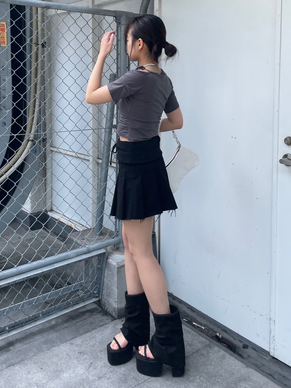 グレー系のTシャツ/カットソー、ブラック系のスカート、ブラック系のサンダルを着用したレディースの春コーディネートの2枚目の写真