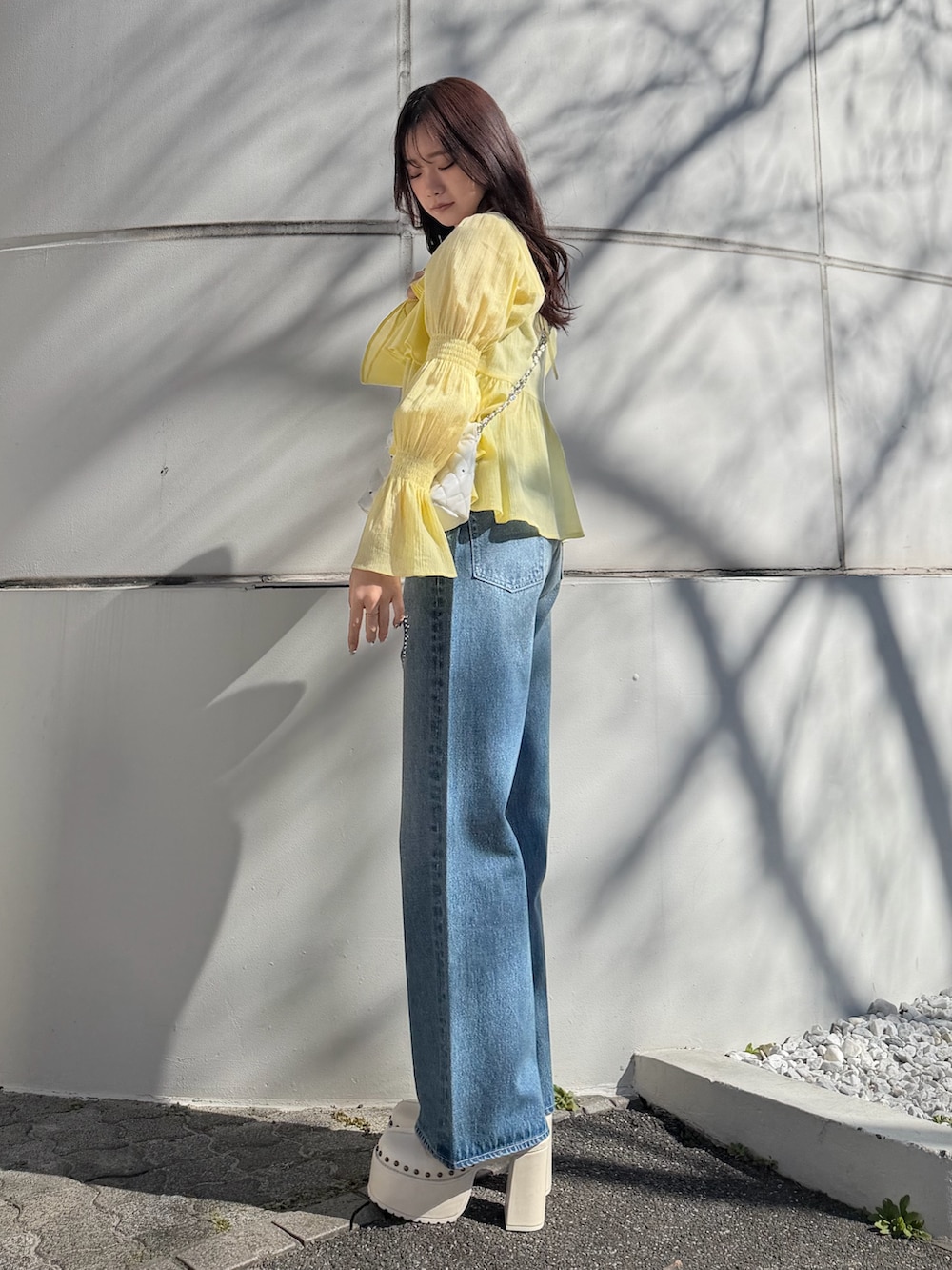 イエロー系のシャツ/ブラウス、ホワイト系のショルダーバッグ、ブルー系のデニムパンツを着用したレディースの春コーディネートの2枚目の写真