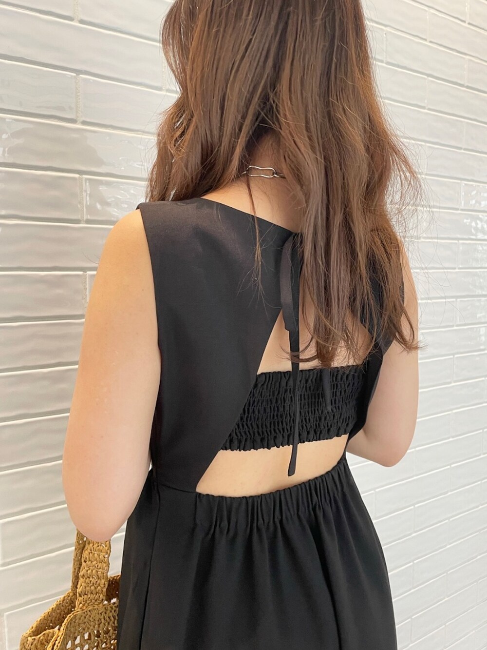 ブラック系のワンピース、ベージュ系のトートバッグ、ホワイト系のサンダルを着用したレディースの夏コーディネートの4枚目の写真