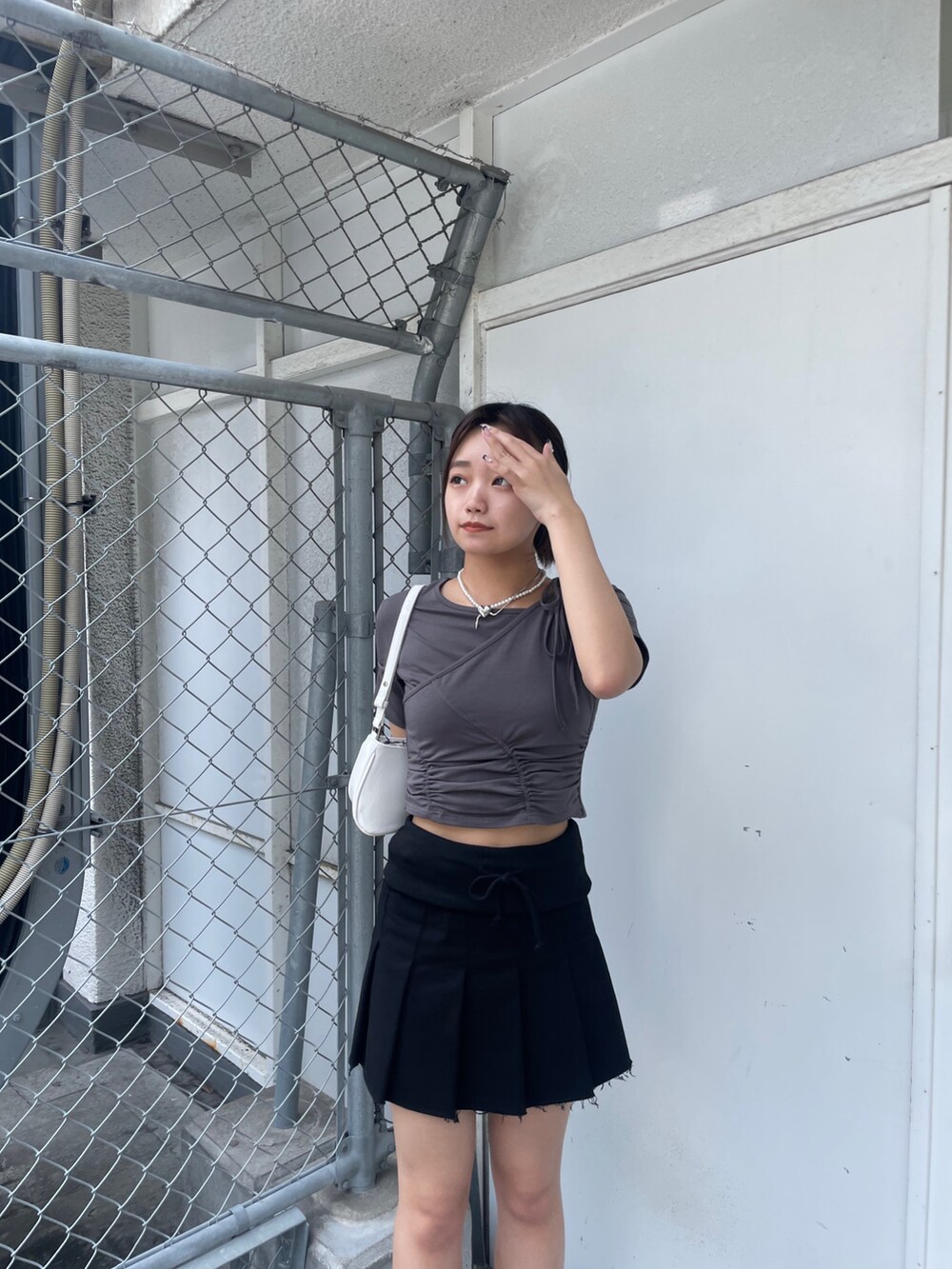 グレー系のTシャツ/カットソー、ブラック系のスカート、ブラック系のサンダルを着用したレディースの春コーディネートの4枚目の写真