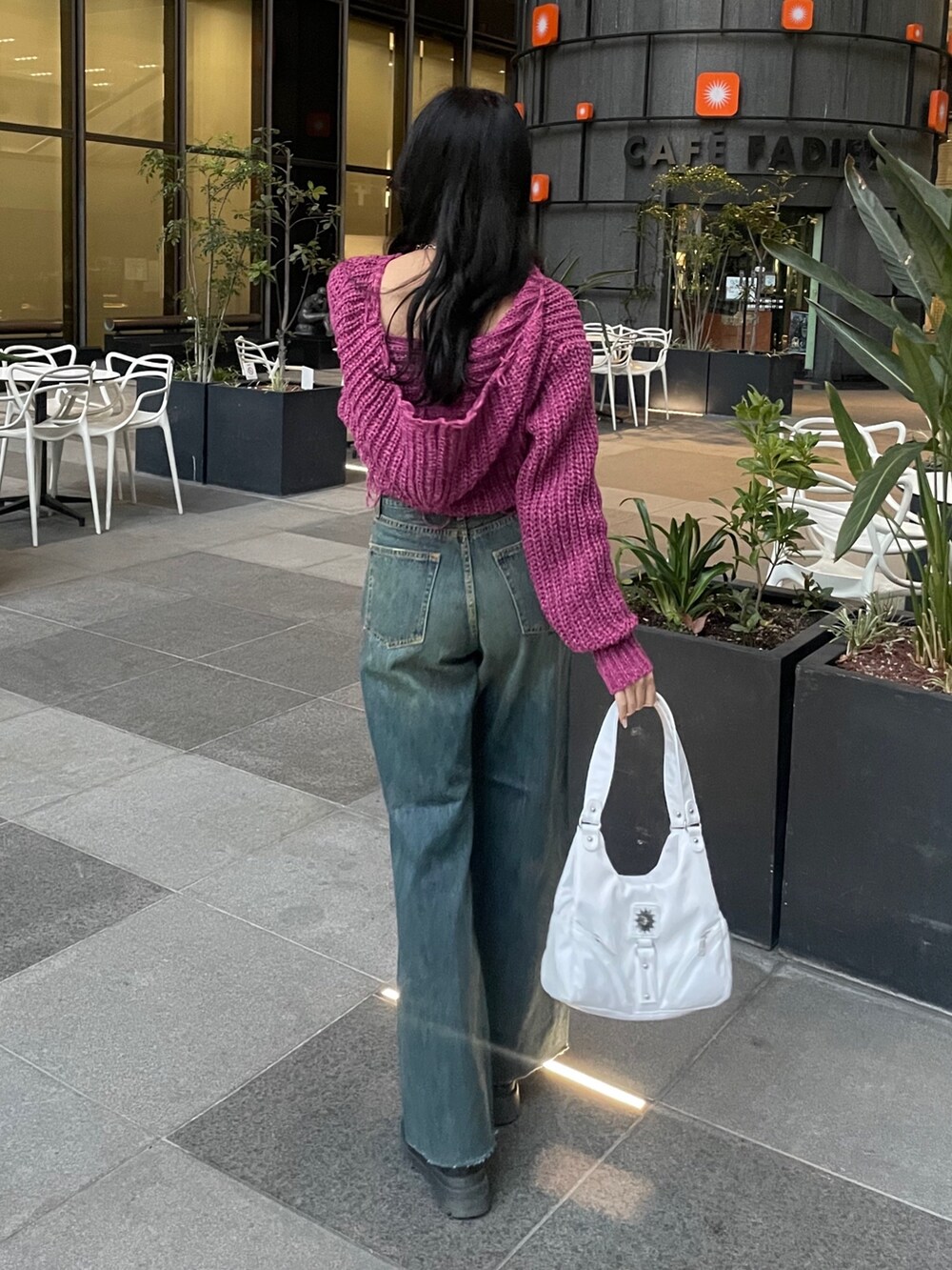 パープル系のニット/セーター、ホワイト系のハンドバッグ、ブルー系のデニムパンツを着用したレディースの冬コーディネートの2枚目の写真