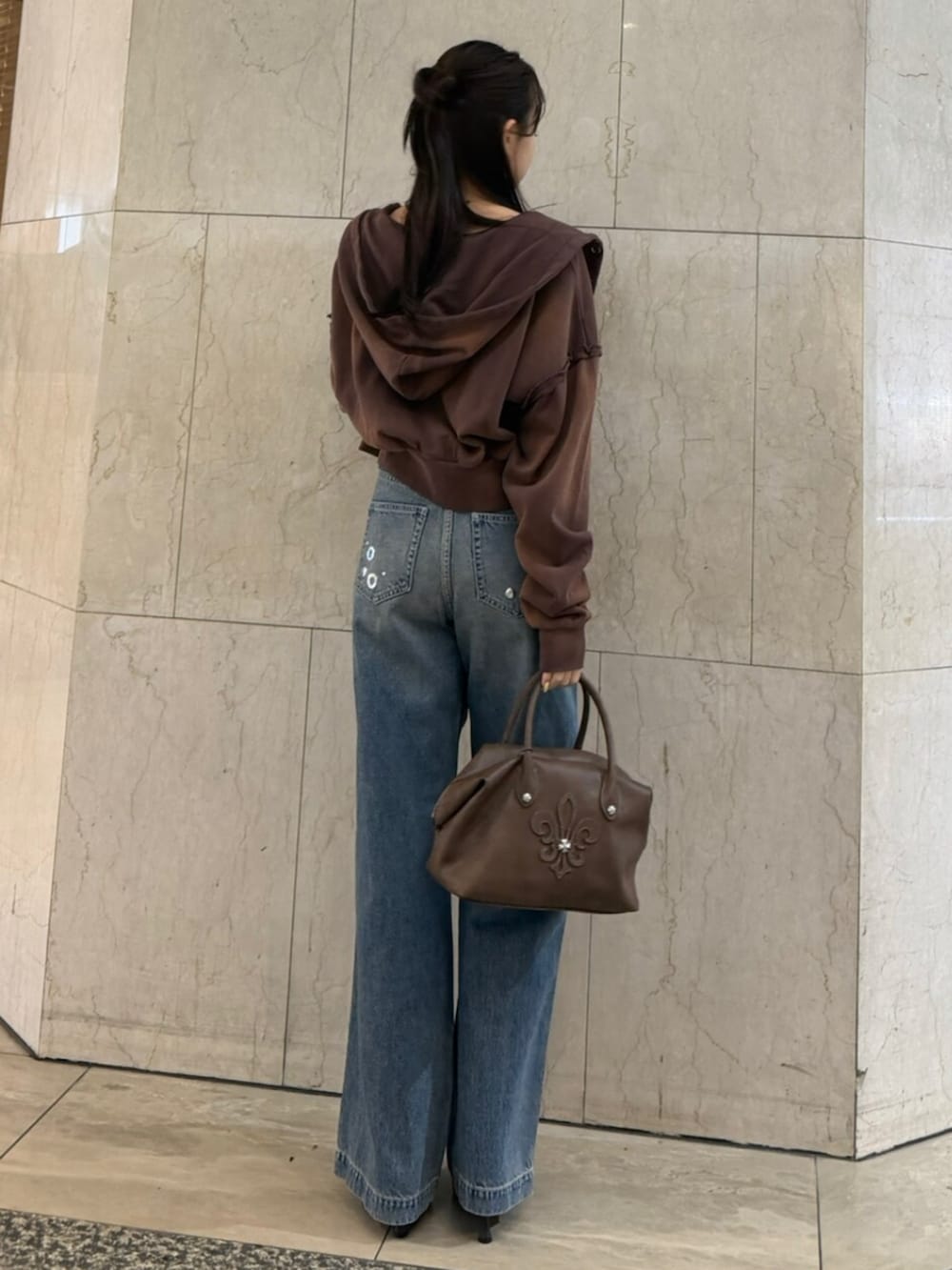 ブラウン系のボストンバッグ、ブラウン系のパーカー、ブラック系のTシャツ/カットソーを着用したレディースの春コーディネートの3枚目の写真