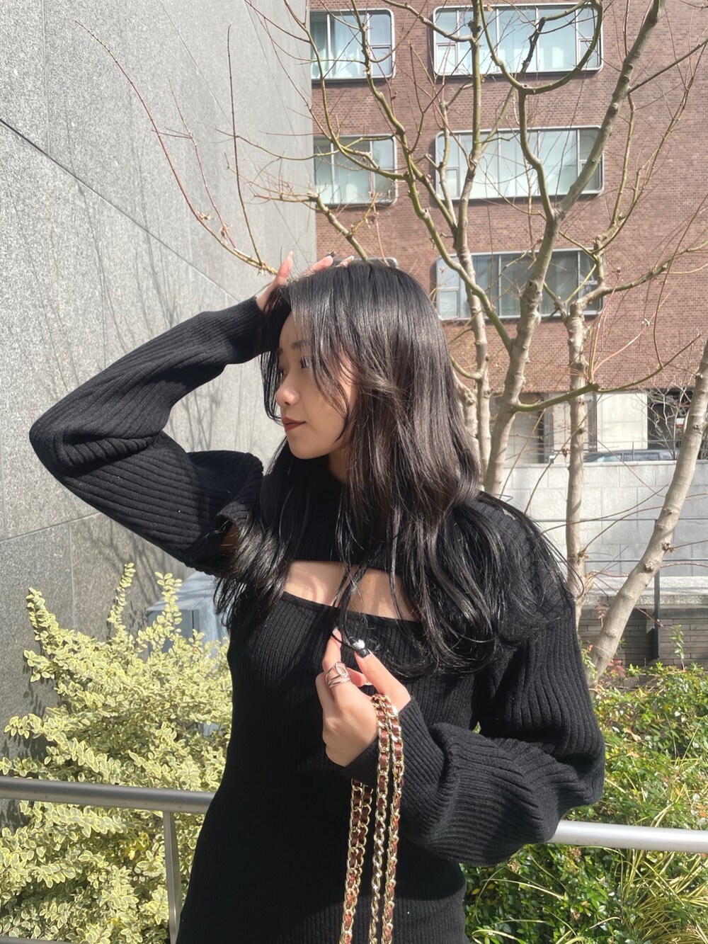 ブラック系のワンピース、ピンク系のショルダーバッグ、ブラック系のブーツを着用したレディースの冬コーディネートの3枚目の写真