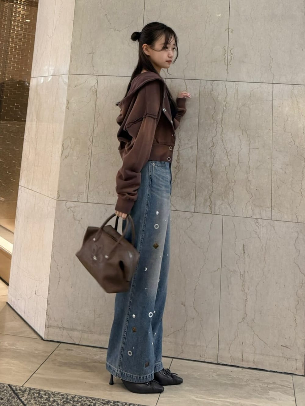 ブラウン系のボストンバッグ、ブラウン系のパーカー、ブラック系のTシャツ/カットソーを着用したレディースの春コーディネートの2枚目の写真