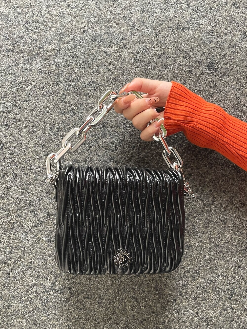 オレンジ系のニット/セーター、ブラック系のデニムパンツ、ブラック系のショルダーバッグを着用したレディースの秋コーディネートの4枚目の写真