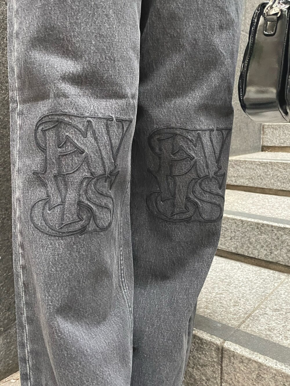 オレンジ系のニット/セーター、ブラック系のデニムパンツ、ブラック系のショルダーバッグを着用したレディースの秋コーディネートの3枚目の写真