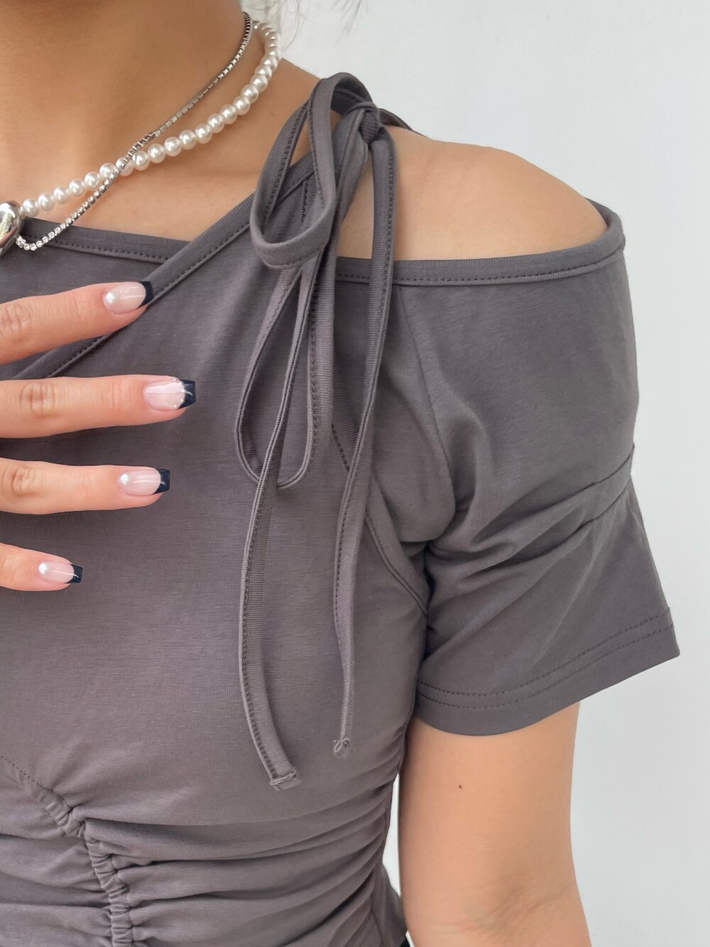 グレー系のTシャツ/カットソー、ブラック系のスカート、ブラック系のサンダルを着用したレディースの春コーディネートの5枚目の写真