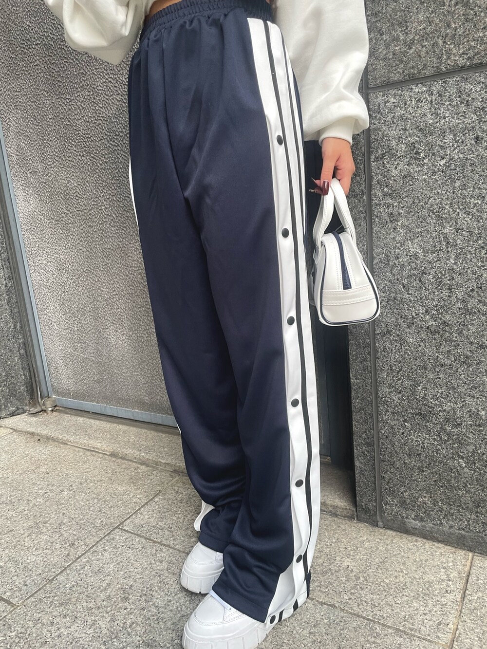 ホワイト系のスウェット、ブルー系のその他パンツ、ホワイト系のハンドバッグを着用したレディースの秋コーディネートの4枚目の写真