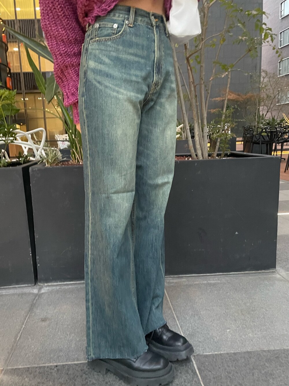 パープル系のニット/セーター、ホワイト系のハンドバッグ、ブルー系のデニムパンツを着用したレディースの冬コーディネートの4枚目の写真