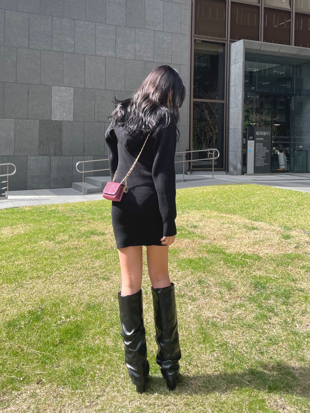 ブラック系のワンピース、ピンク系のショルダーバッグ、ブラック系のブーツを着用したレディースの冬コーディネートの2枚目の写真