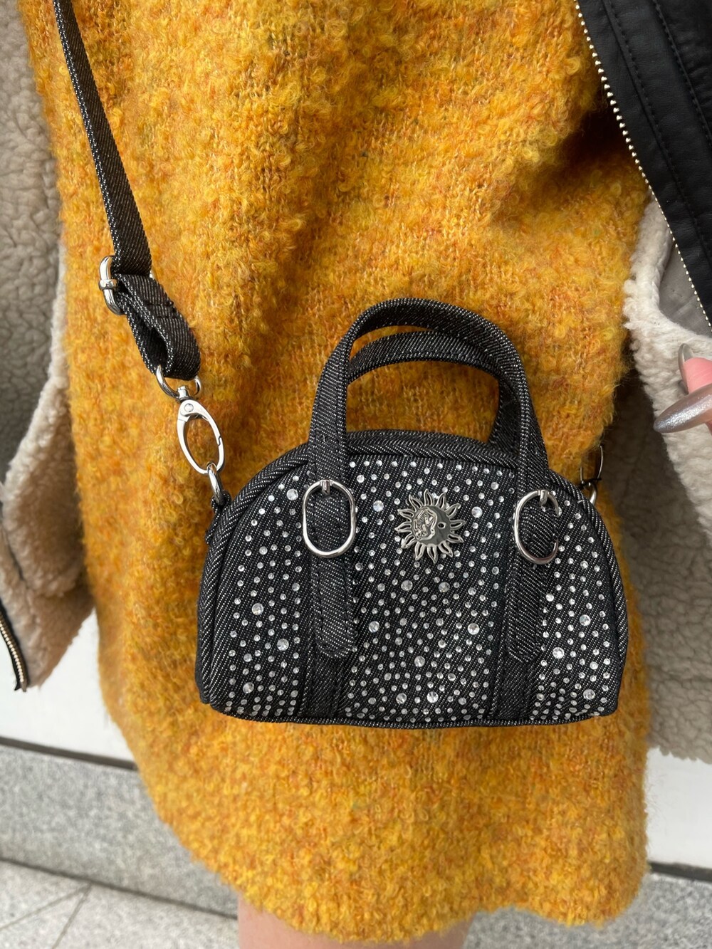 その他のムートンコート、イエロー系のニット/セーター、ブラック系のハンドバッグを着用したレディースの冬コーディネートの3枚目の写真