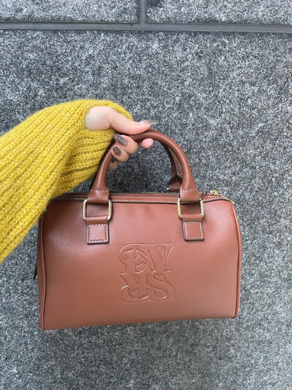 イエロー系のニット/セーター、ブルー系のデニムパンツ、ブラウン系のボストンバッグを着用したレディースの秋コーディネートの4枚目の写真