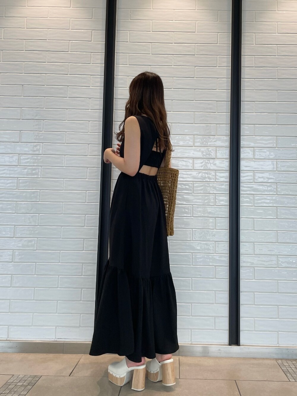 ブラック系のワンピース、ベージュ系のトートバッグ、ホワイト系のサンダルを着用したレディースの夏コーディネートの3枚目の写真