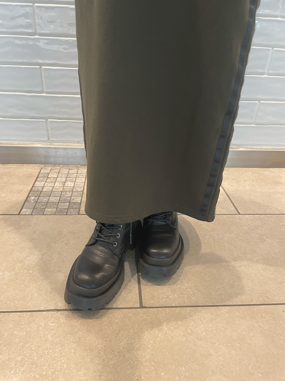 グリーン系のセットアップ、ブラック系のハンドバッグ、ブラック系のブーツを着用したレディースの秋コーディネートの4枚目の写真