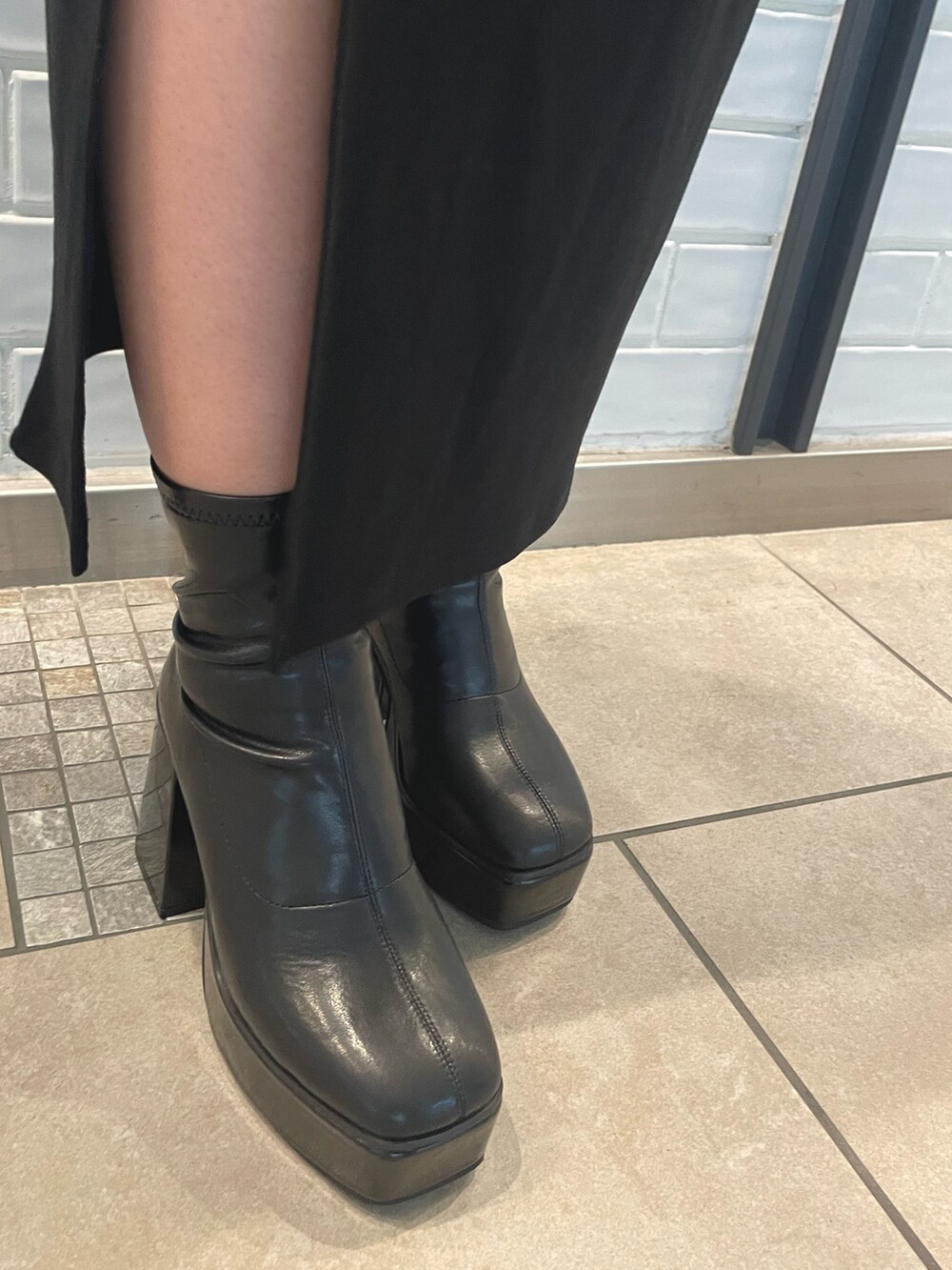 ブラック系のワンピース、ブラック系のブーツ、レッド系のショルダーバッグを着用したレディースの秋コーディネートの4枚目の写真