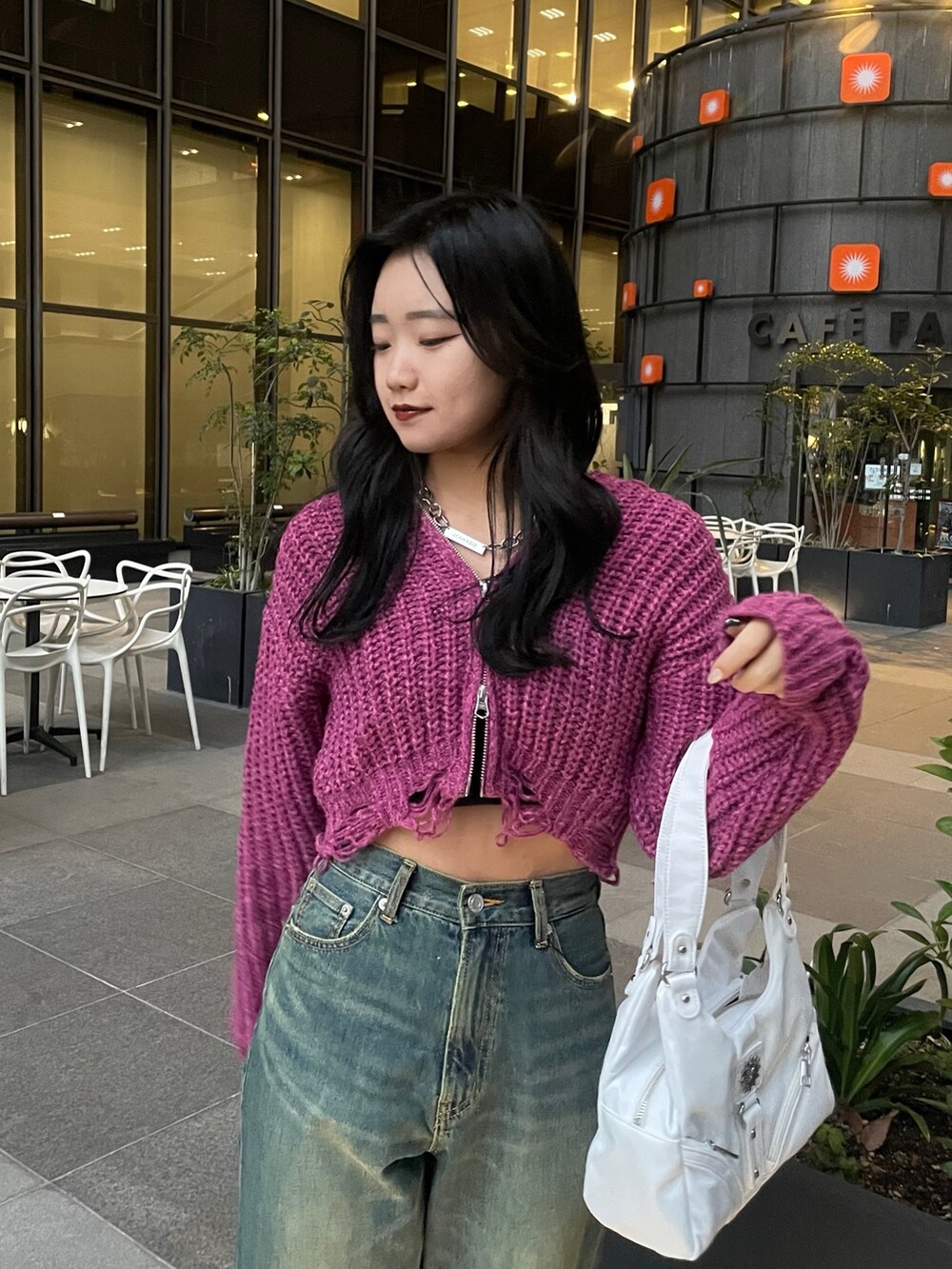 パープル系のニット/セーター、ホワイト系のハンドバッグ、ブルー系のデニムパンツを着用したレディースの冬コーディネートの3枚目の写真