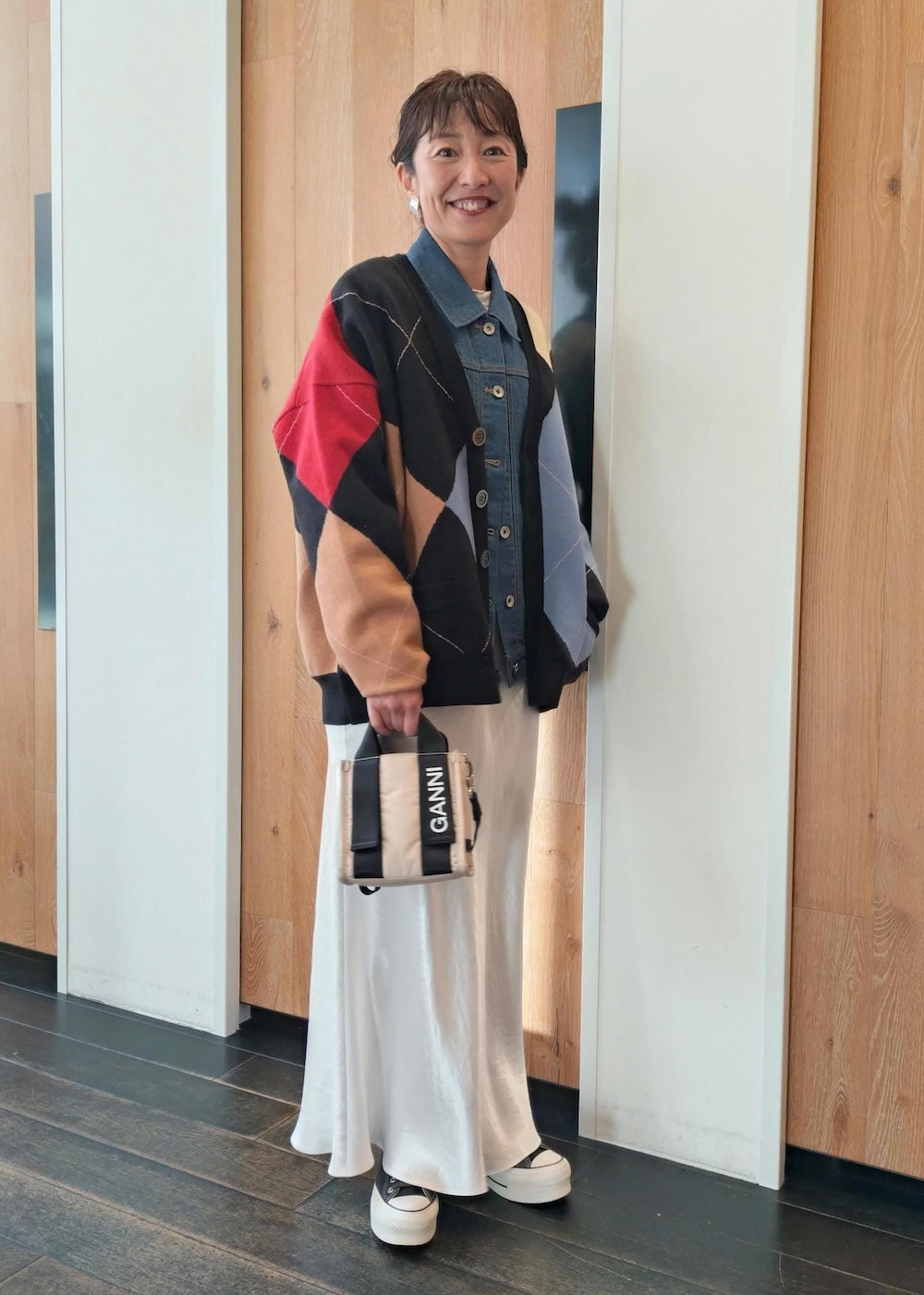 ベージュ系のトートバッグ、ブラック系のカーディガン/ボレロ、ホワイト系のスカートを着用したレディースの冬コーディネートの2枚目の写真