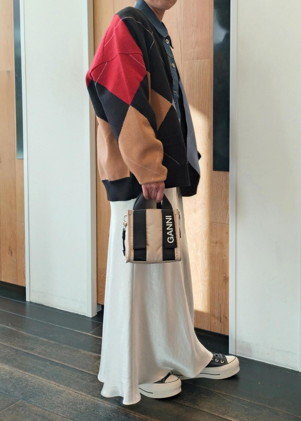 ベージュ系のトートバッグ、ブラック系のカーディガン/ボレロ、ホワイト系のスカートを着用したレディースの冬コーディネートの5枚目の写真